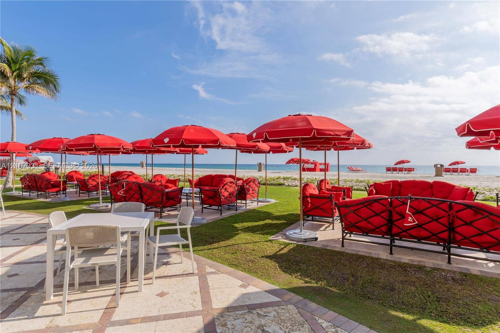 Outdoor terrace featuring stone paver flooring and manicured grass lawn with direct beach access