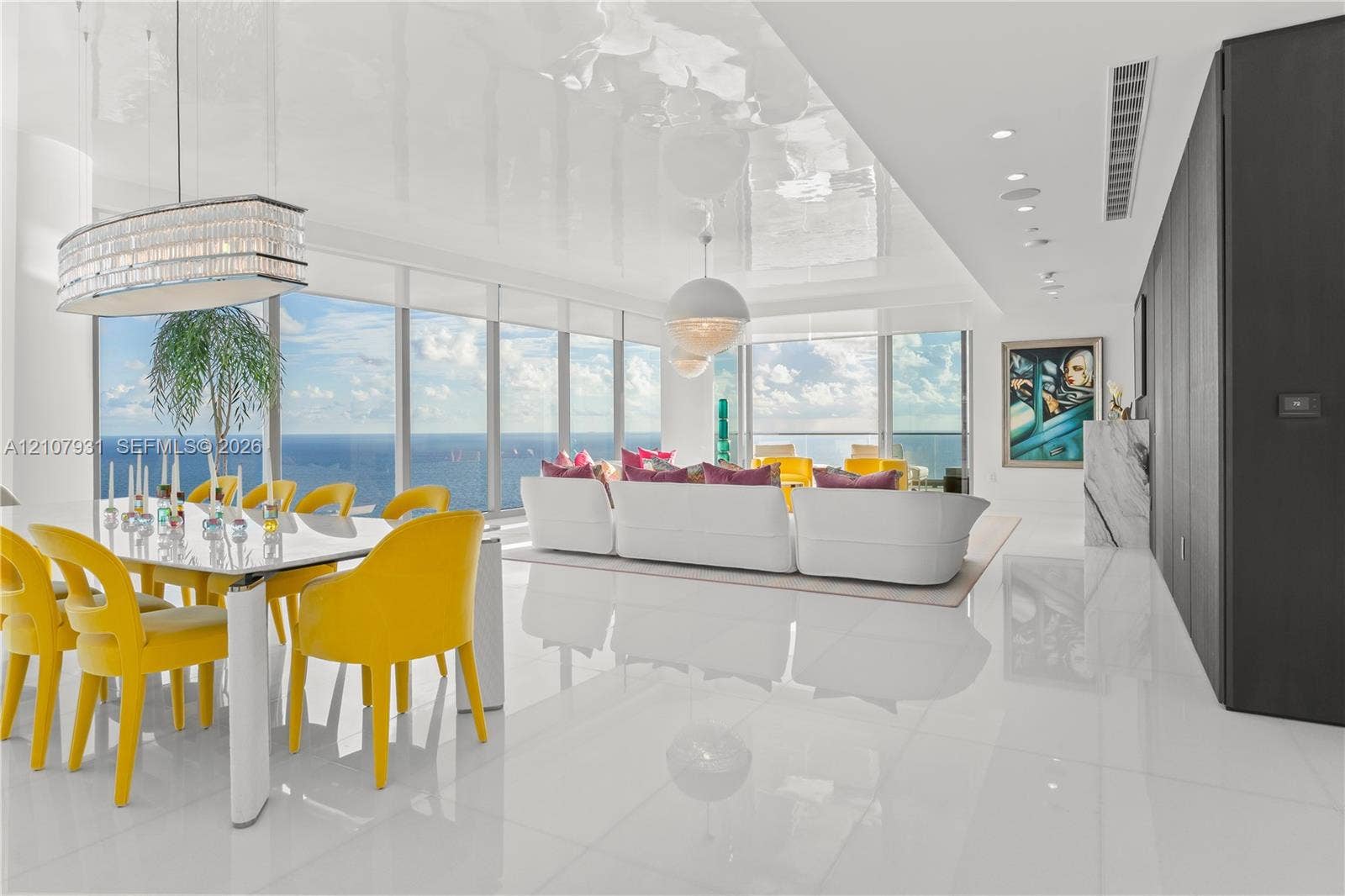 Open-concept interior featuring high-gloss flooring, floor-to-ceiling windows, panoramic ocean scenery, recessed lighting, and a crystal-accented chandelier