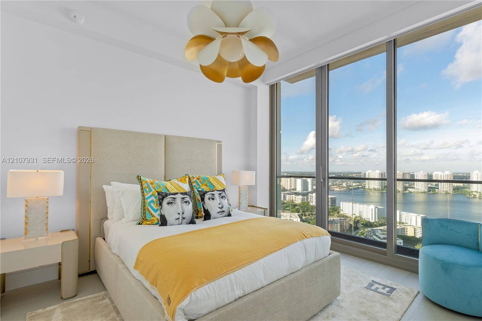 Floor-to-ceiling windows featuring panoramic water and city scenery, combined with a sculptural multi-tiered pendant light fixture