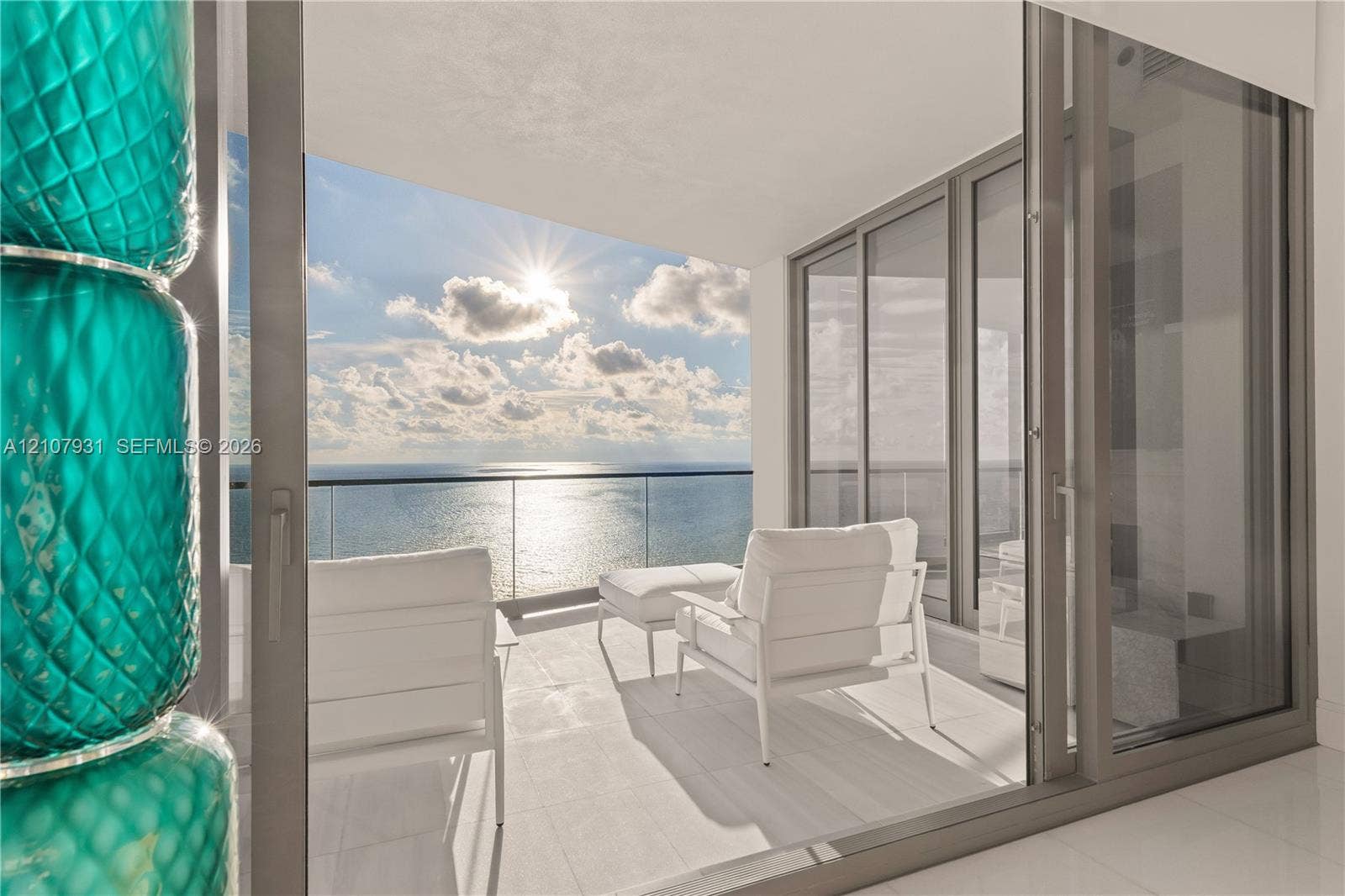 Covered balcony featuring large-format tile flooring, frameless glass railing, and floor-to-ceiling sliding glass doors