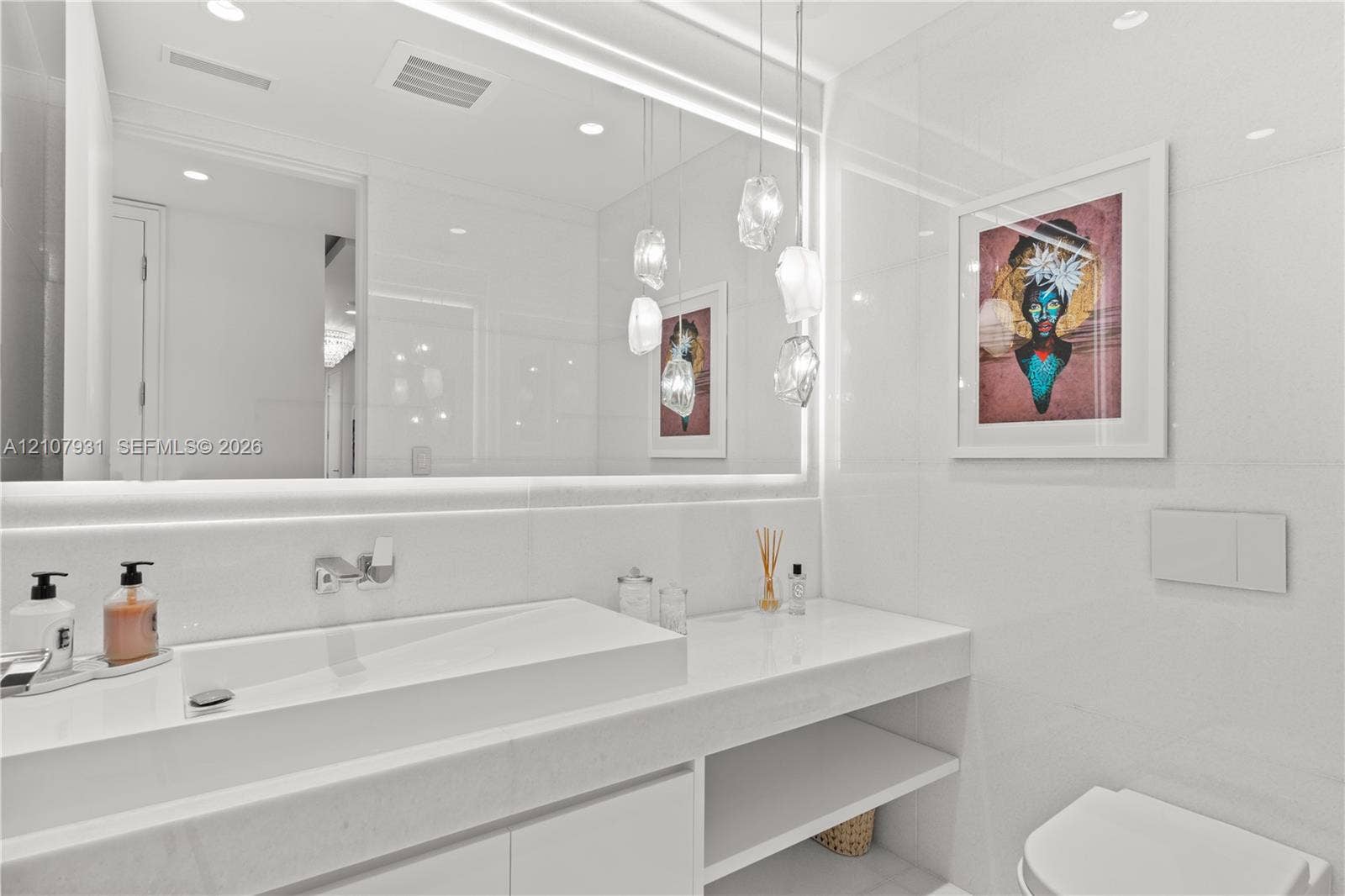 Floating vanity with an integrated basin, expansive wall-to-wall mirror, tiered glass pendant lighting, and recessed ceiling illumination