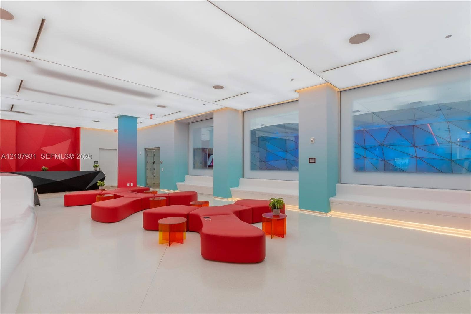 Modern interior space featuring an expansive ceiling with integrated recessed lighting, built-in tiered perimeter seating, smooth-finish flooring, and structural columns with gradient coloring