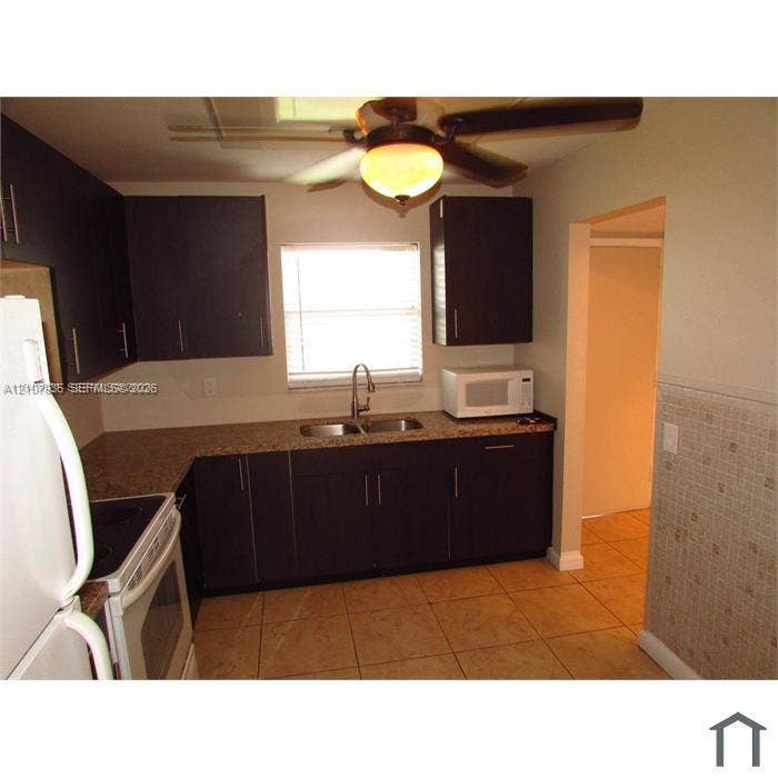 2839 Taylor Street, #3, Hollywood, Hollywood, FL 33020 Kitchen featuring dark-toned cabinetry, stone-finish countertops, stainless steel dual-basin sink with arched faucet, ceramic tile flooring, and ceiling fan with integrated lighting