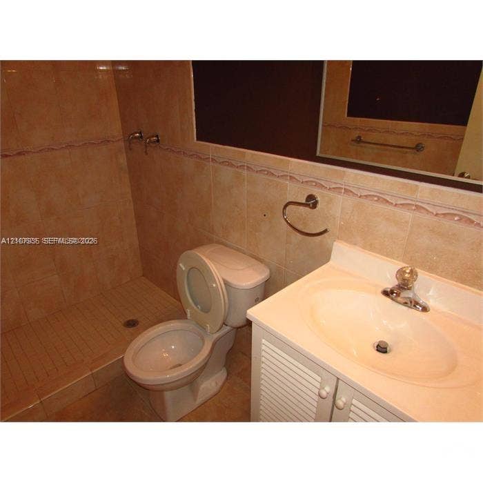 2839 Taylor Street, #3, Hollywood, Hollywood, FL 33020 Bathroom featuring full-height wall tiling with decorative accent trim, a stall shower, a vanity with a molded countertop and integrated basin, and louvered-style cabinet doors
