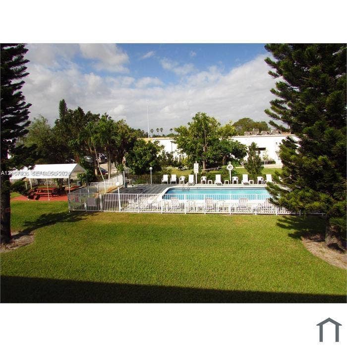 2839 Taylor Street, #3, Hollywood, Hollywood, FL 33020 Outdoor swimming pool featuring a perimeter fence, a covered patio area, and mature landscaping within a manicured lawn