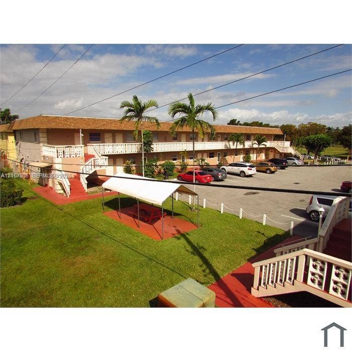 2839 Taylor Street, #3, Hollywood, Hollywood, FL 33020 Multi-story building with a shingle-style roof, exterior staircases, designated paved parking area, and landscaped grounds featuring palm trees