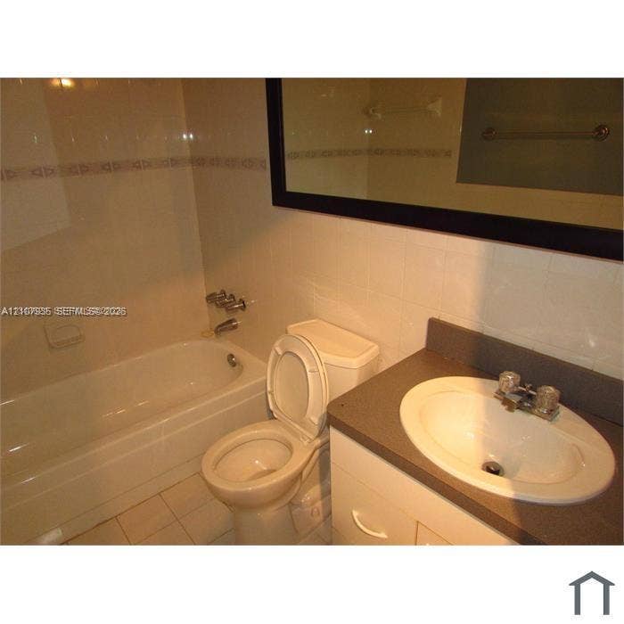 2839 Taylor Street, #3, Hollywood, Hollywood, FL 33020 Bathroom featuring a built-in vanity with a stone-finish countertop, undermount sink, porcelain tile flooring, and a recessed bathtub with tile surround