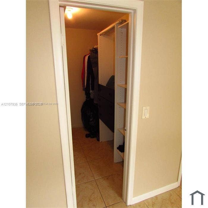2839 Taylor Street, #3, Hollywood, Hollywood, FL 33020 Walk-in closet featuring floor-to-ceiling shelving, built-in storage drawers, a hanging rod, and ceramic tile flooring