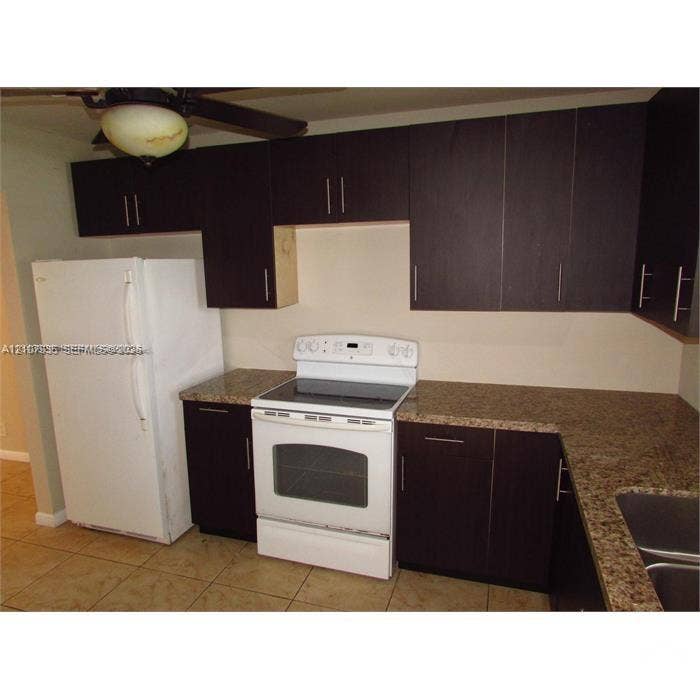 2839 Taylor Street, #3, Hollywood, Hollywood, FL 33020 Kitchen featuring dark wood-finish cabinetry, stone-surface countertops, dual-basin stainless steel sink, and white appliances including a freestanding range and refrigerator