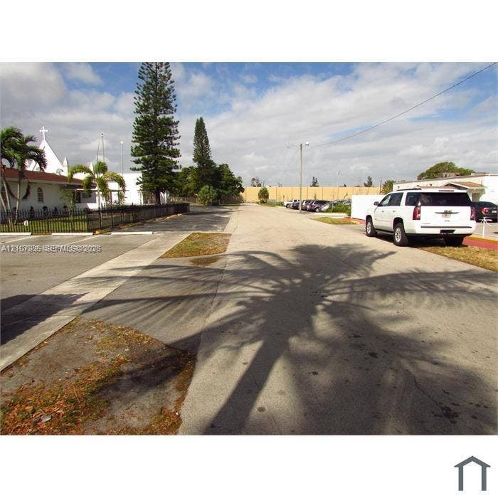 2839 Taylor Street, #3, Hollywood, Hollywood, FL 33020 Paved parking area with concrete curbing, decorative metal fencing, and mature landscaping