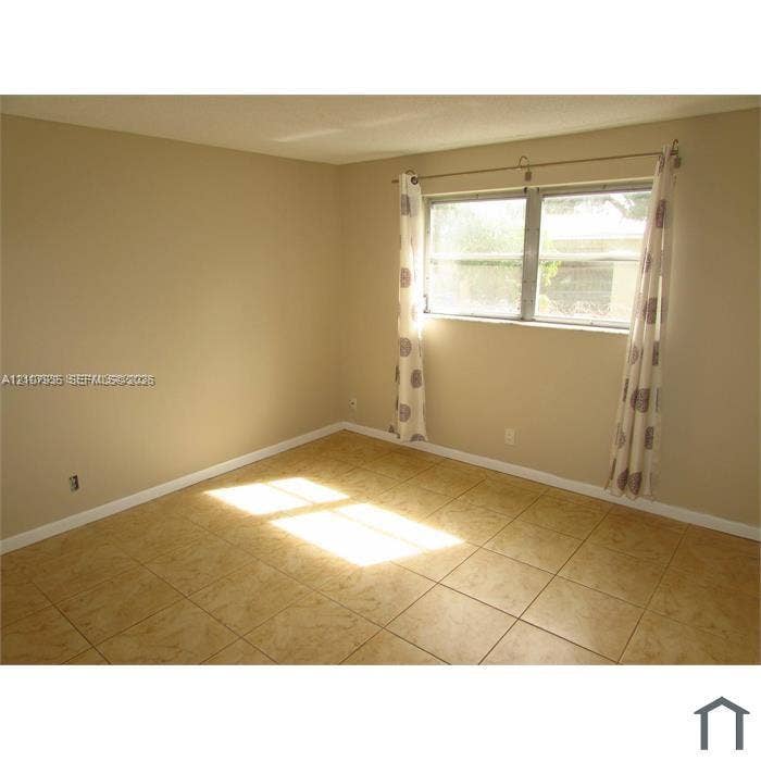 2839 Taylor Street, #3, Hollywood, Hollywood, FL 33020 Neutral-toned interior room featuring large-format ceramic tile flooring, a horizontal sliding window, and a metal curtain rod fixture