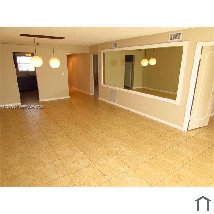 2839 Taylor Street, #3, Hollywood, Hollywood, FL 33020 Neutral-toned interior space featuring light-colored square tile flooring, a large wall-mounted mirror with white trim, and a modern two-globe pendant light fixture
