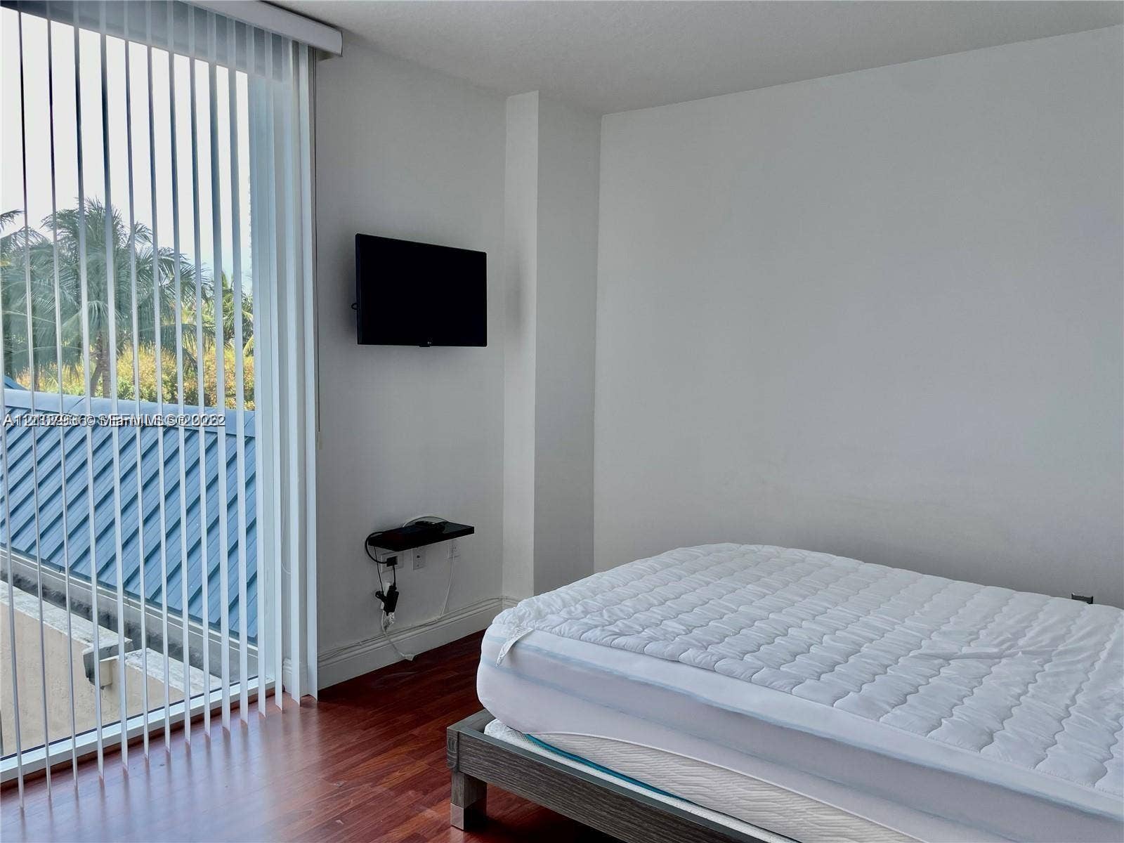 3370 Hidden Bay Drive, #510, Aventura, FL 33180 Floor-to-ceiling vertical blinds, wood-finish flooring, and a wall-mounted floating media shelf