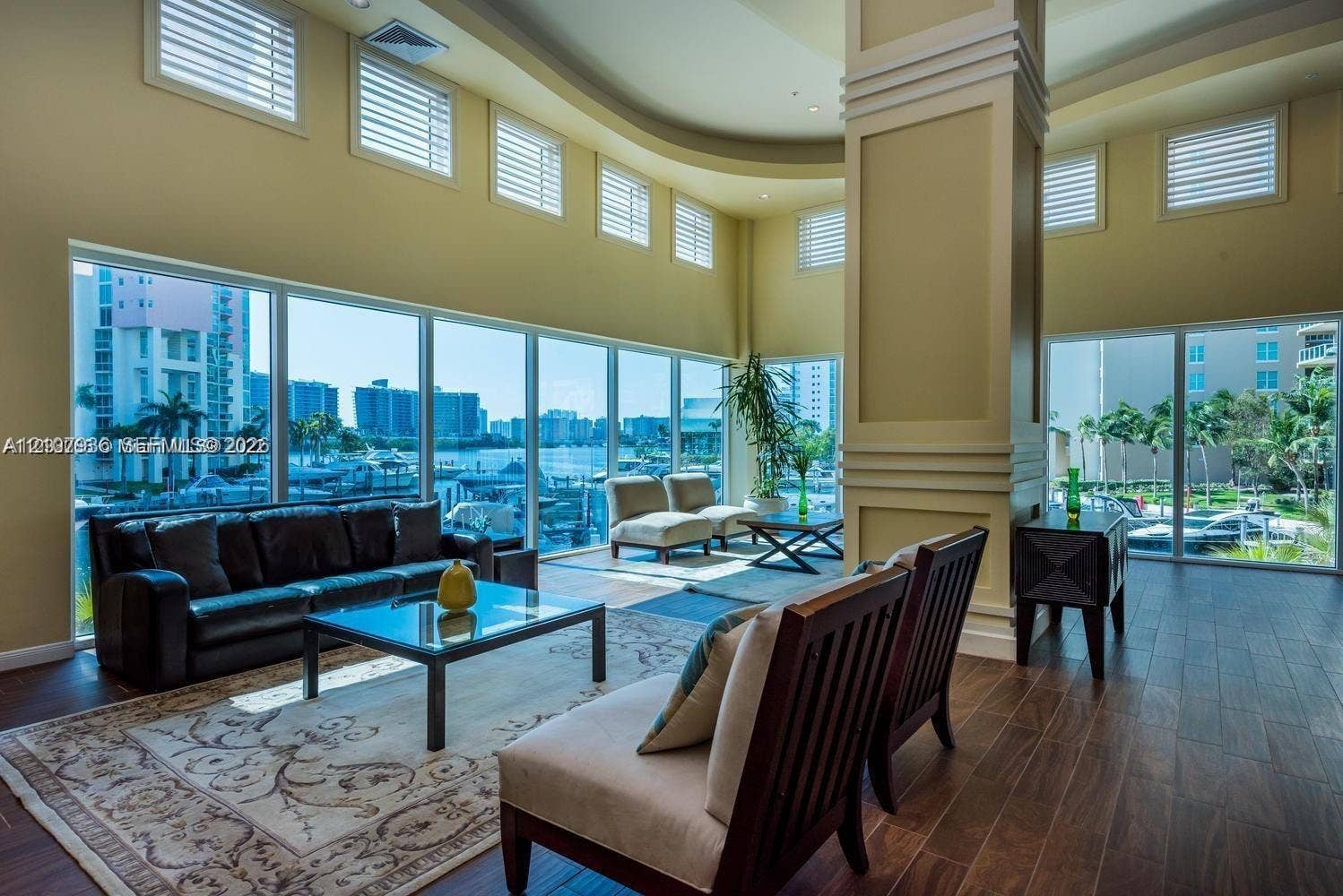 3370 Hidden Bay Drive, #510, Aventura, FL 33180 Expansive living space featuring floor-to-ceiling windows, soaring tray ceilings, decorative millwork on a prominent support column, and wood-finish flooring