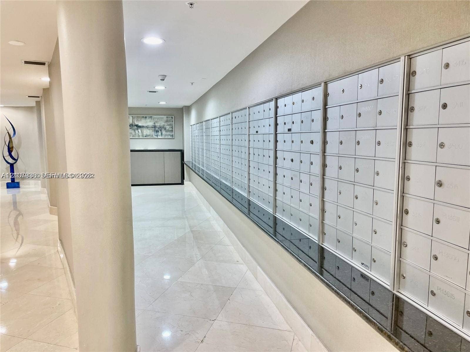 3370 Hidden Bay Drive, #510, Aventura, FL 33180 Common area mail center featuring a wall of individual metal mailboxes, a dark stone ledge, recessed ceiling lighting, and polished stone tile flooring