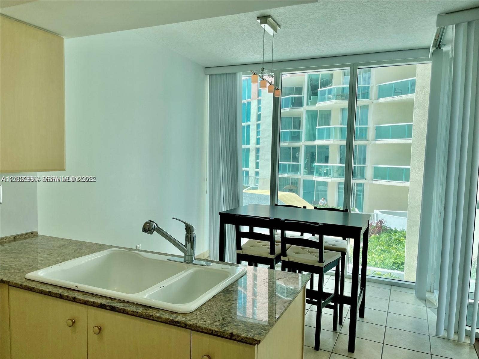 3370 Hidden Bay Drive, #510, Aventura, FL 33180 Kitchen featuring stone-composite countertops, dual-basin sink, high-arc faucet, tile flooring, and floor-to-ceiling glass paneling