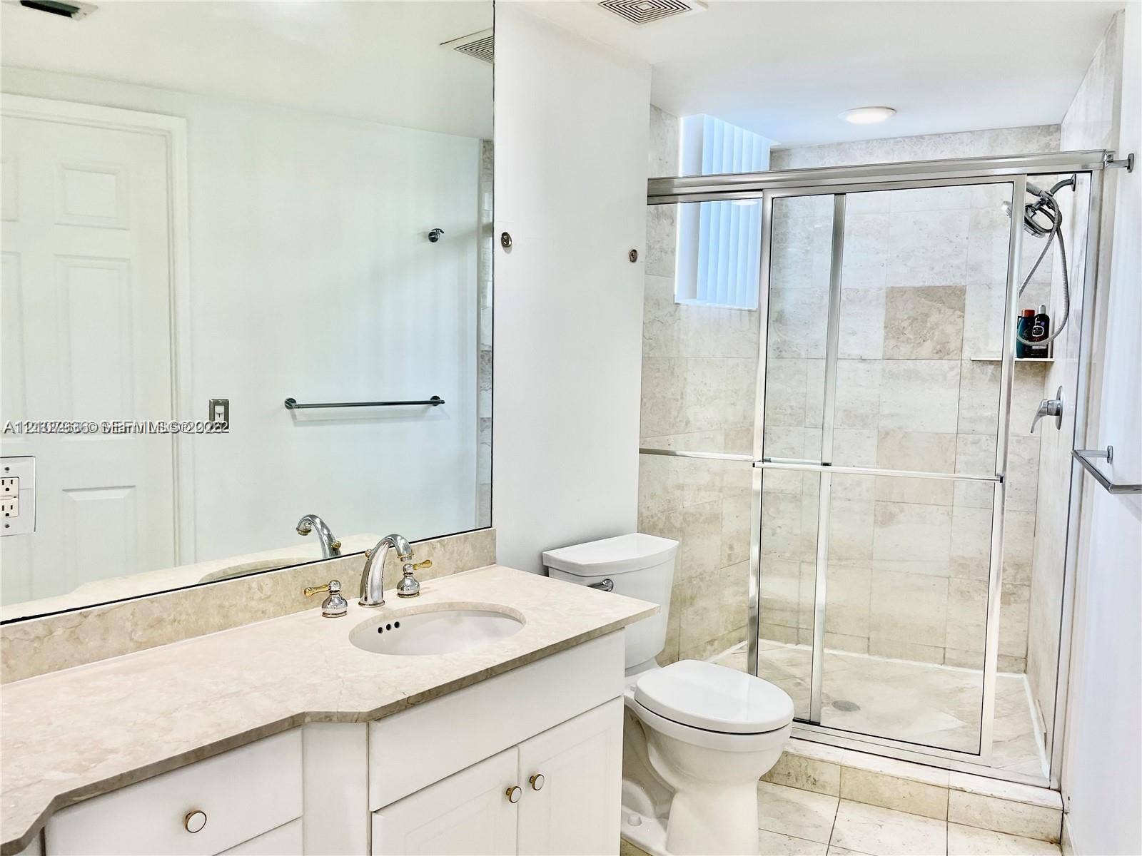 3370 Hidden Bay Drive, #510, Aventura, FL 33180 Bathroom featuring a vanity with a stone countertop, an integrated sink, an expansive wall-mounted mirror, a glass-enclosed shower with stone tile surround, and tile flooring