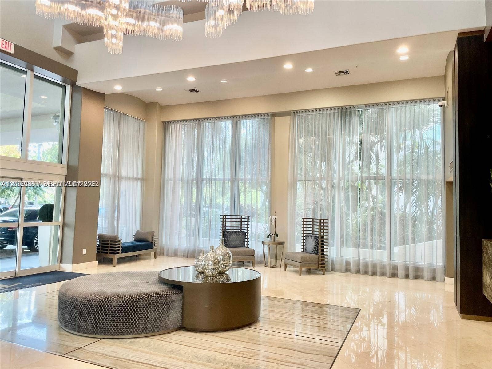3370 Hidden Bay Drive, #510, Aventura, FL 33180 Grand foyer featuring high ceilings, large-format stone tile flooring, expansive floor-to-ceiling windows, and a decorative chandelier