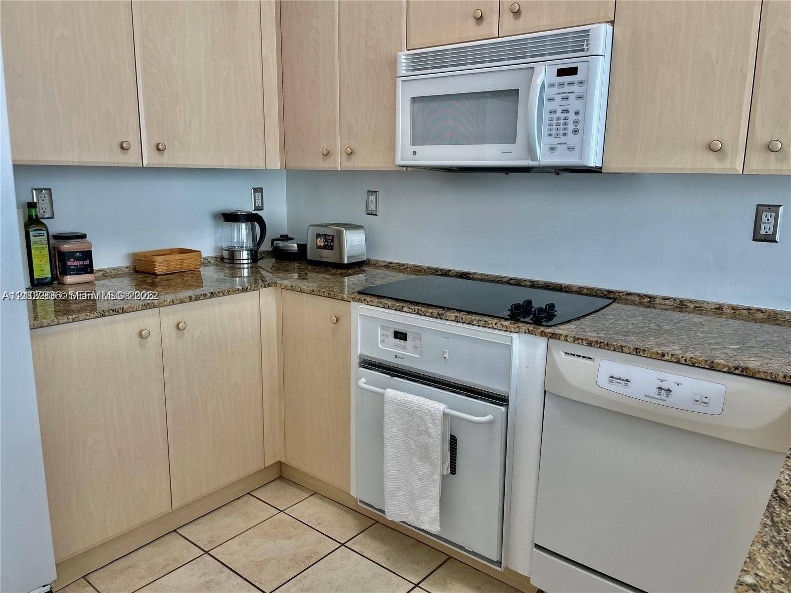 3370 Hidden Bay Drive, #510, Aventura, FL 33180 Kitchen featuring light-finish cabinetry, stone-texture countertops, ceramic tile flooring, and built-in appliances including a microwave, oven, and dishwasher
