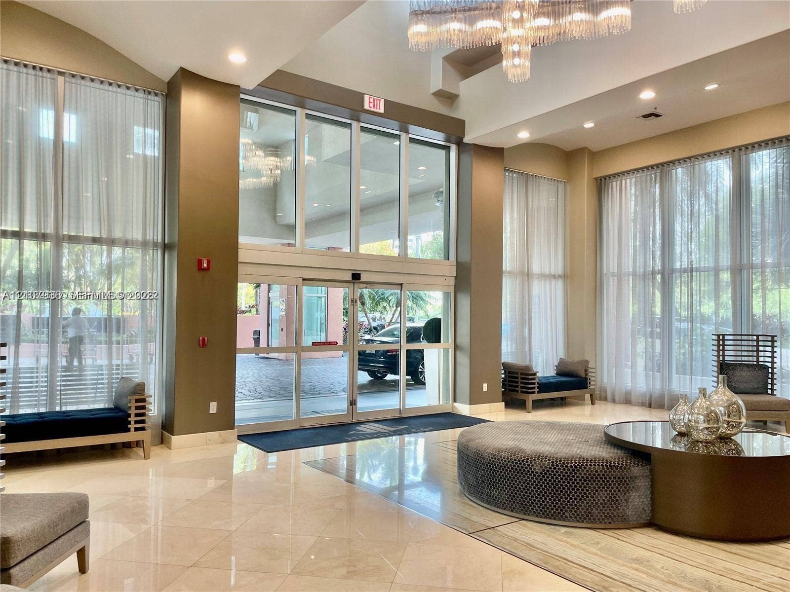 3370 Hidden Bay Drive, #510, Aventura, FL 33180 Double-height glass entrance featuring soaring floor-to-ceiling windows, polished stone flooring, recessed lighting, and a multi-tiered crystal chandelier