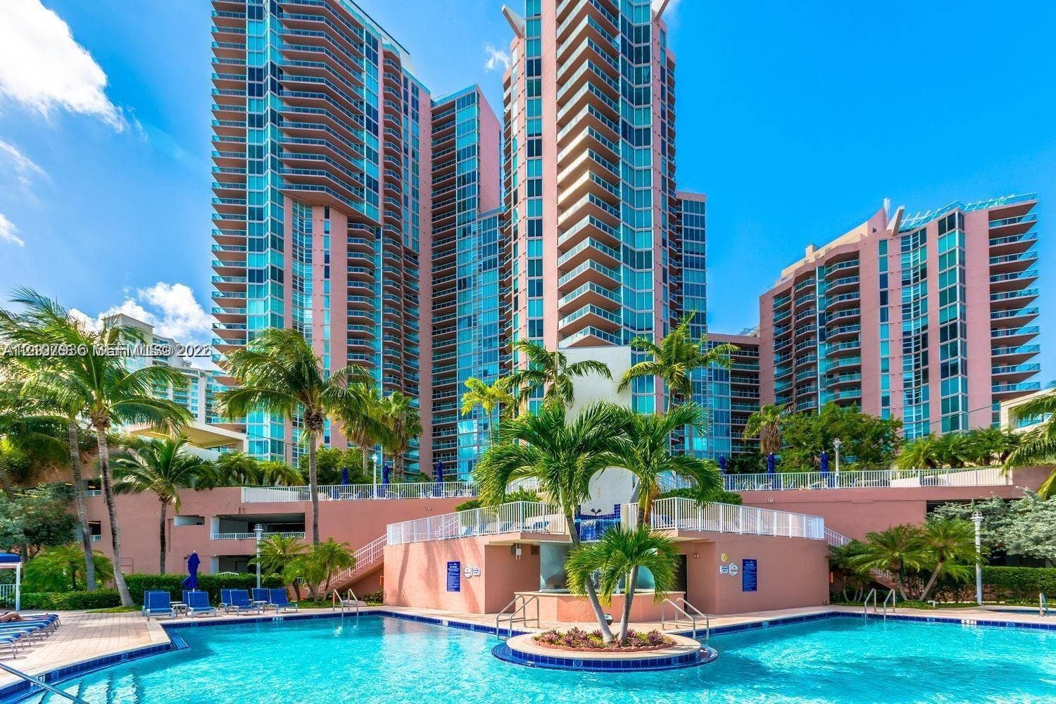 3370 Hidden Bay Drive, #510, Aventura, FL 33180 High-rise residential exterior featuring expansive glass balconies, an outdoor swimming pool, integrated landscaping, and a central raised island planter