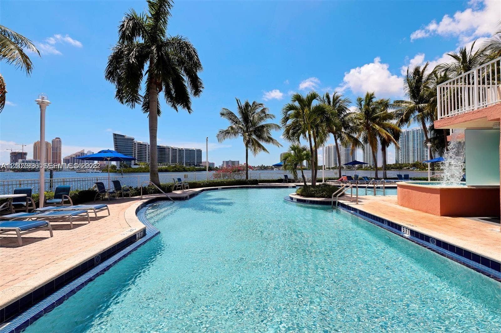 3370 Hidden Bay Drive, #510, Aventura, FL 33180 Waterfront swimming pool with an integrated spa, featuring paved decking and mature palm trees