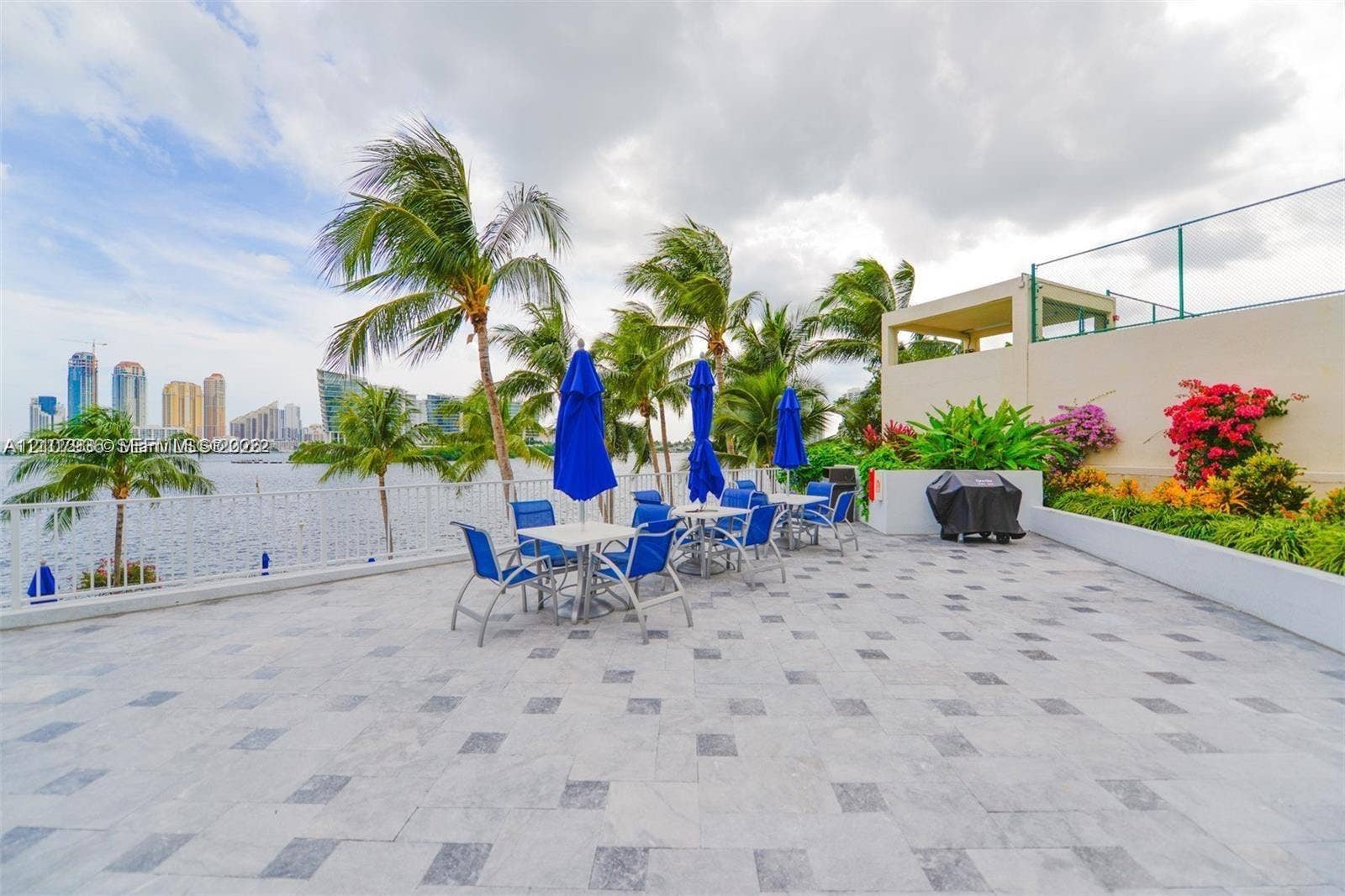 3370 Hidden Bay Drive, #510, Aventura, FL 33180 Expansive waterfront terrace featuring patterned stone tiling, decorative perimeter landscaping, and metal railing