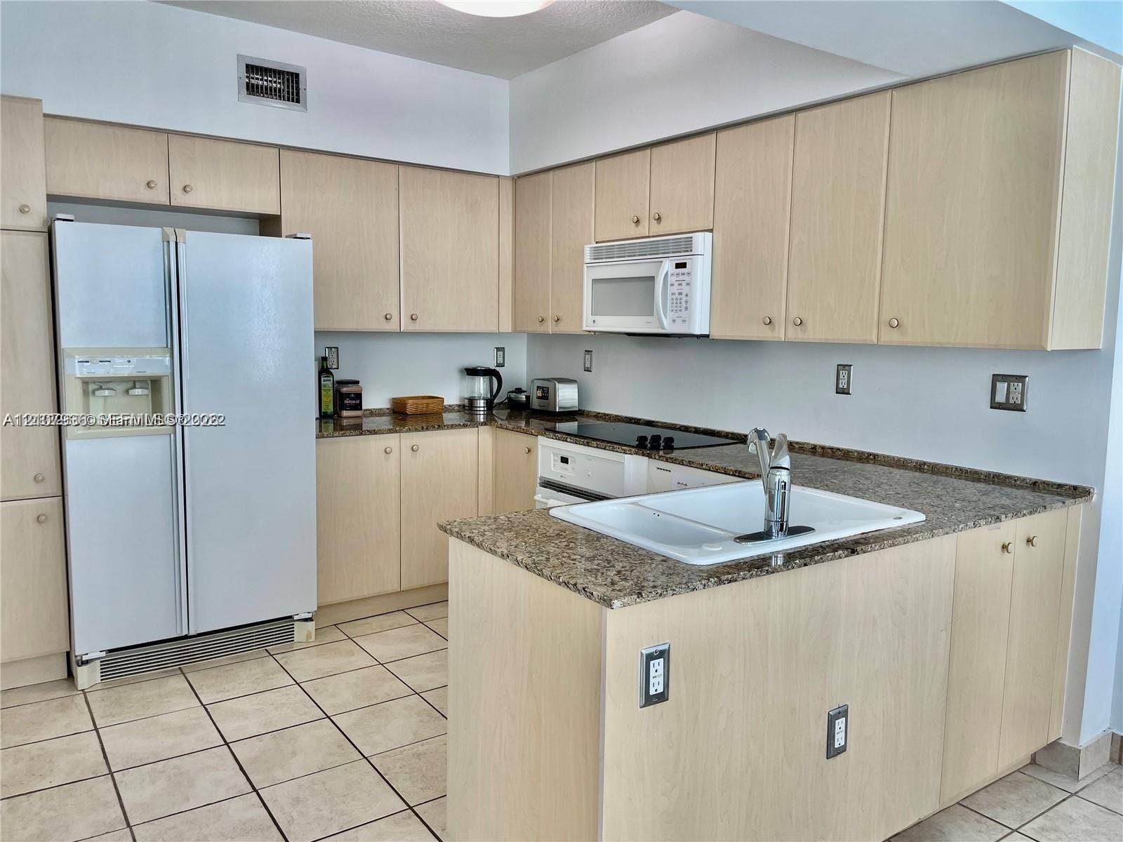 3370 Hidden Bay Drive, #510, Aventura, FL 33180 Kitchen featuring light wood-finish cabinetry, stone-surface countertops, a drop-in white sink with a chrome faucet, and tile flooring