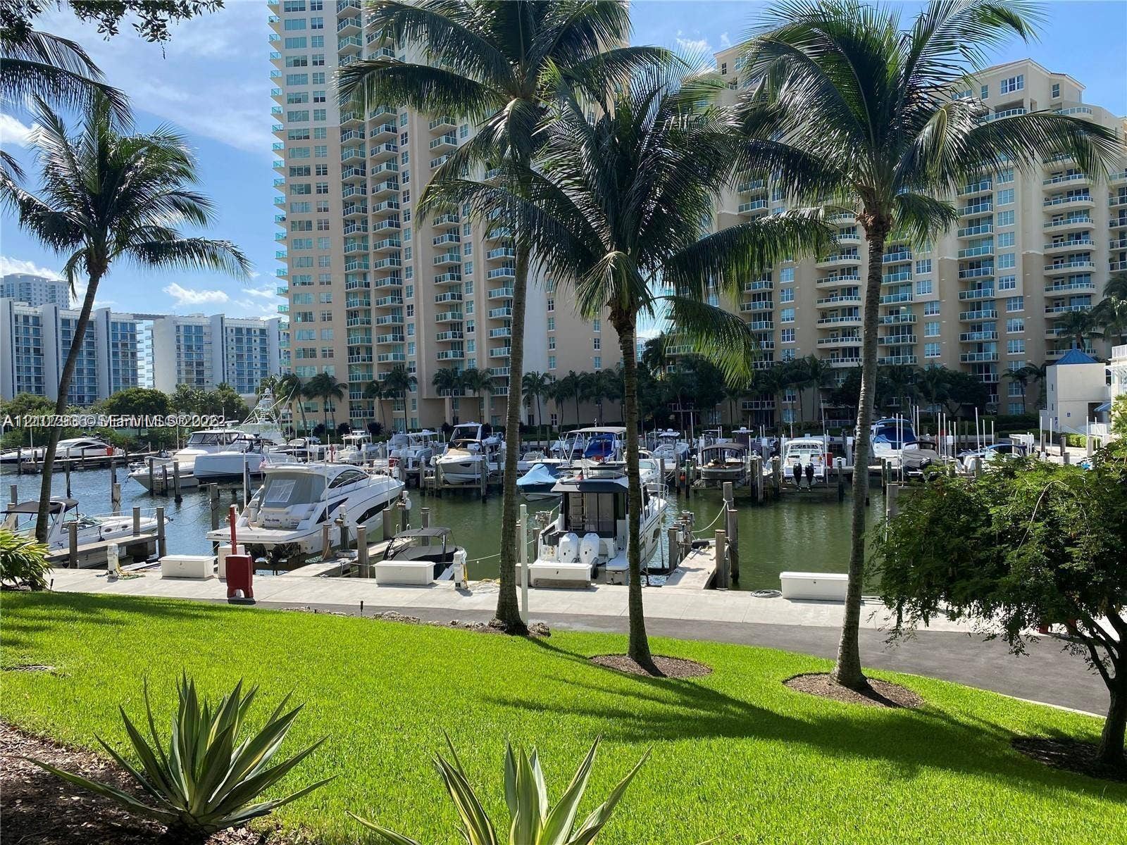 3370 Hidden Bay Drive, #510, Aventura, FL 33180 Marina featuring multiple boat slips, paved waterfront walkway, and manicured green space with mature palm trees