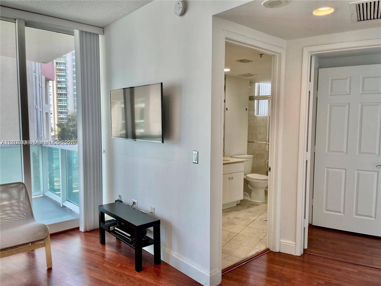 3370 Hidden Bay Drive, #510, Aventura, FL 33180 Floor-to-ceiling glass paneling with sliding door access to a private balcony, wood-finish flooring, and white paneled interior doors
