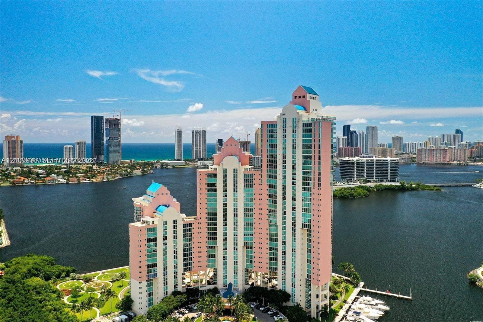 3370 Hidden Bay Drive, #510, Aventura, FL 33180 High-rise building with a tiered architectural design, multi-story glass-paned windows, waterfront location, manicured landscaped grounds, and integrated boat slips