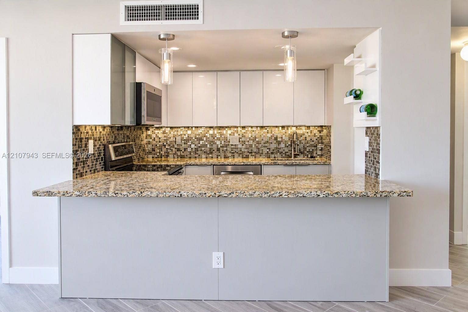 251 174th Street, #201, Sunny Isles Beach, Sunny Isles Beach, FL 33160 Kitchen featuring a stone countertop peninsula, white flat-panel cabinetry, mosaic tile backsplash, stainless steel appliances, and pendant lighting