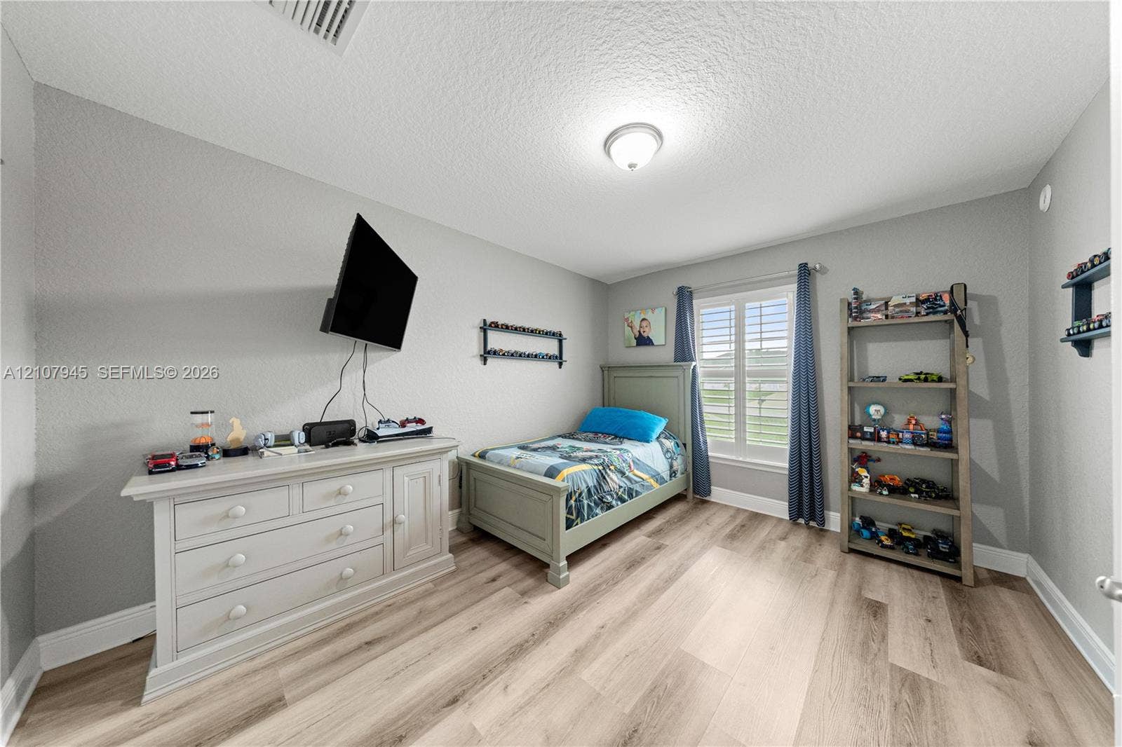 Room featuring neutral-toned walls, wood-finish flooring, and a single window with plantation shutters
