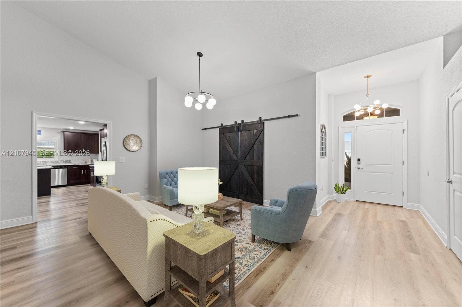 Vaulted ceilings, wood-finish flooring, sliding dark-tone barn doors, and multi-light pendant chandeliers