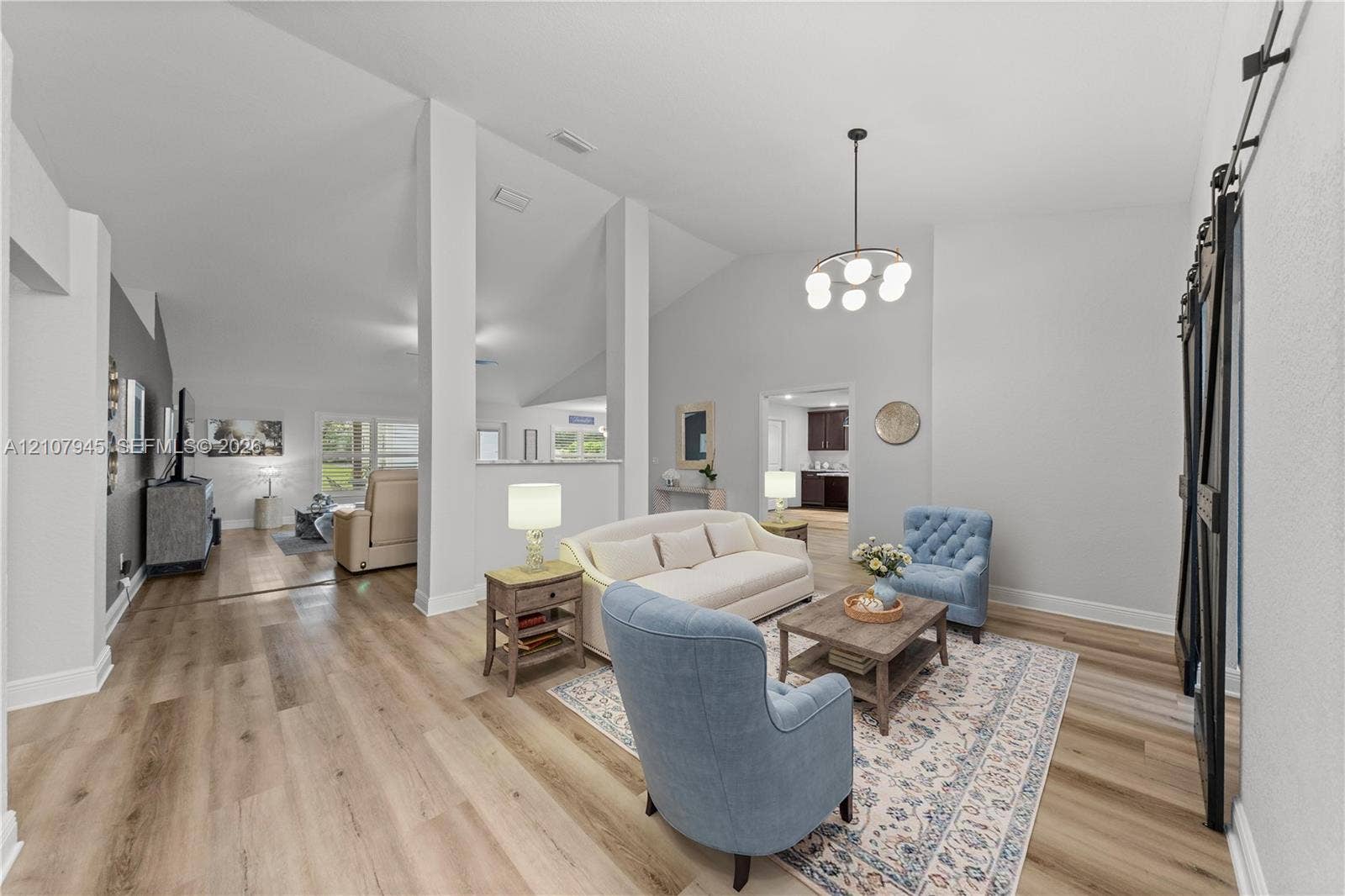 Vaulted ceilings, wood-finish flooring, architectural support pillars, and black barn-style sliding doors