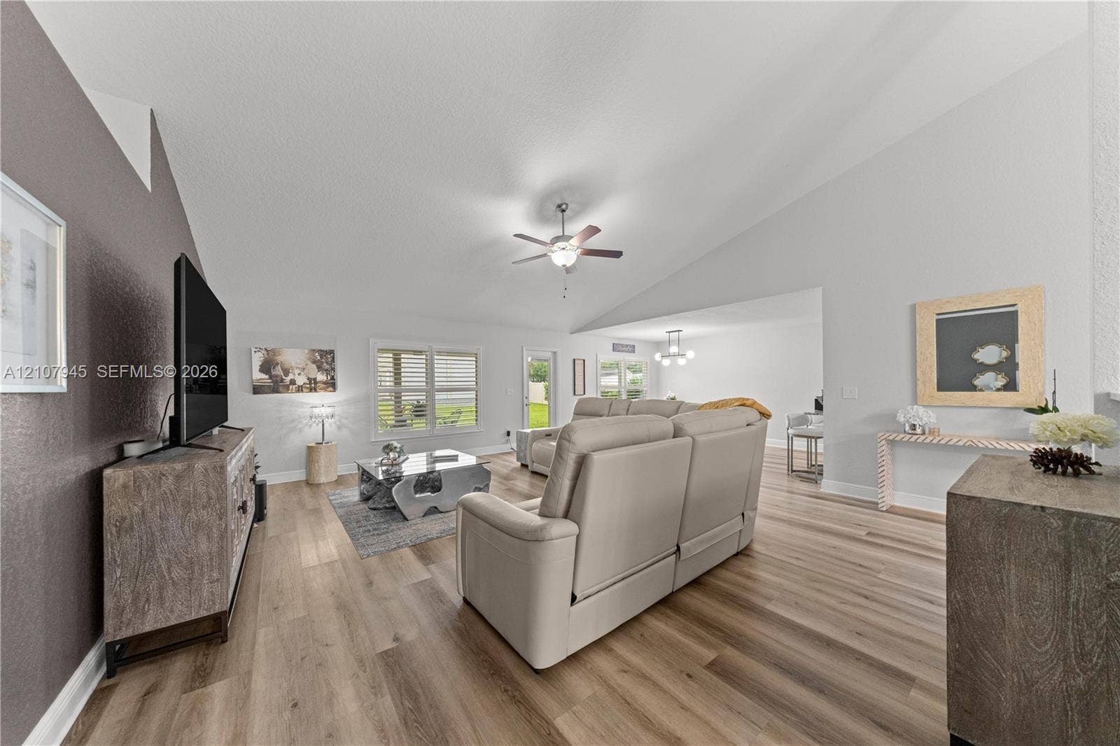 Vaulted ceilings with a central fan, wood-finish flooring, and natural light via horizontal window treatments