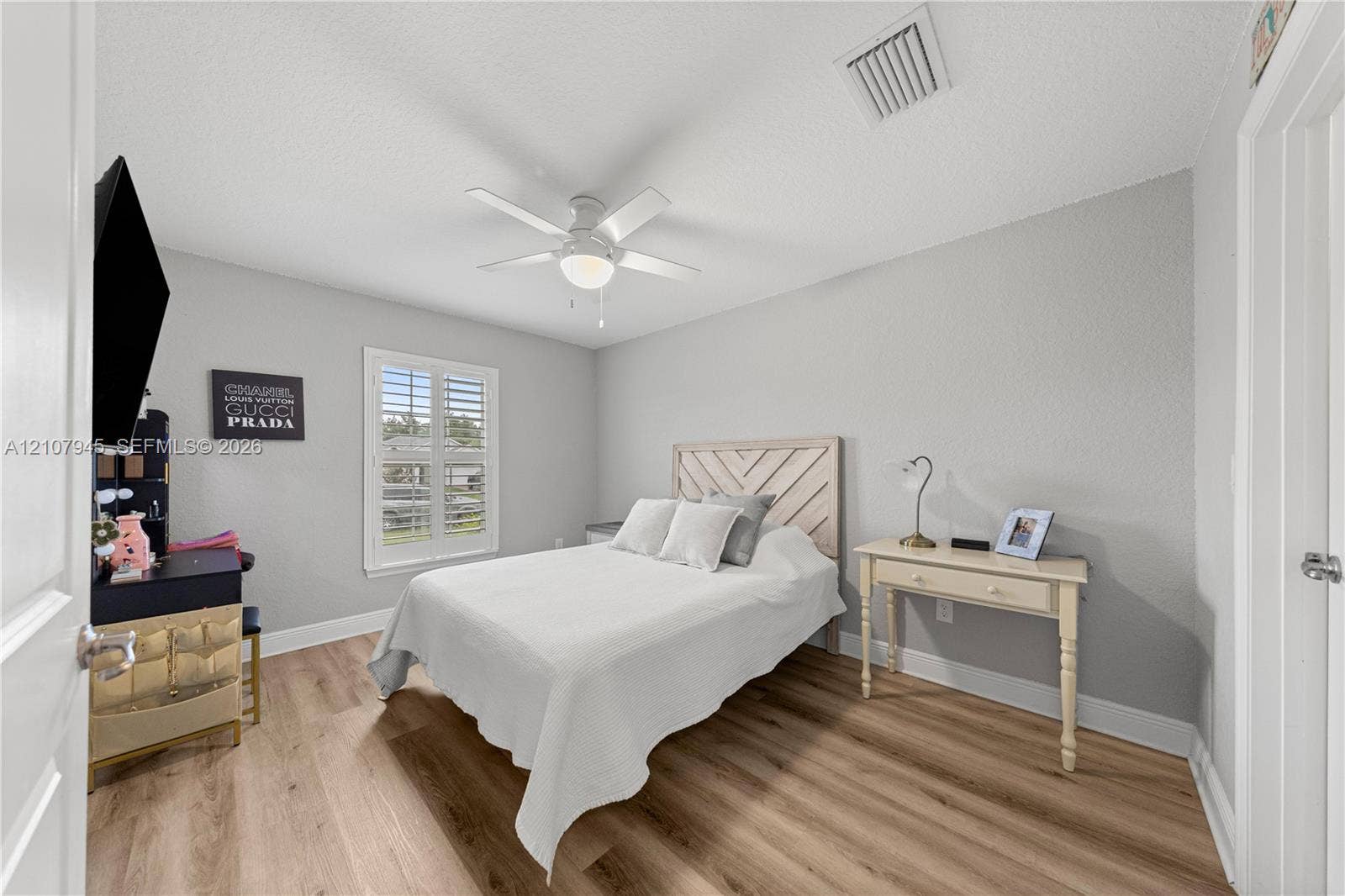 Room featuring wood-finish flooring, plantation shutters, and a central ceiling fan with integrated lighting