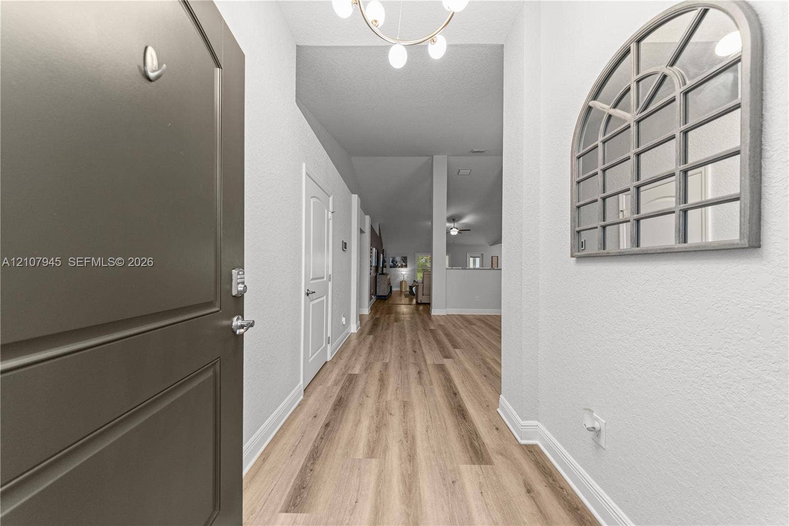 Entryway featuring wood-finish flooring, a multi-light chandelier, and a solid panel door