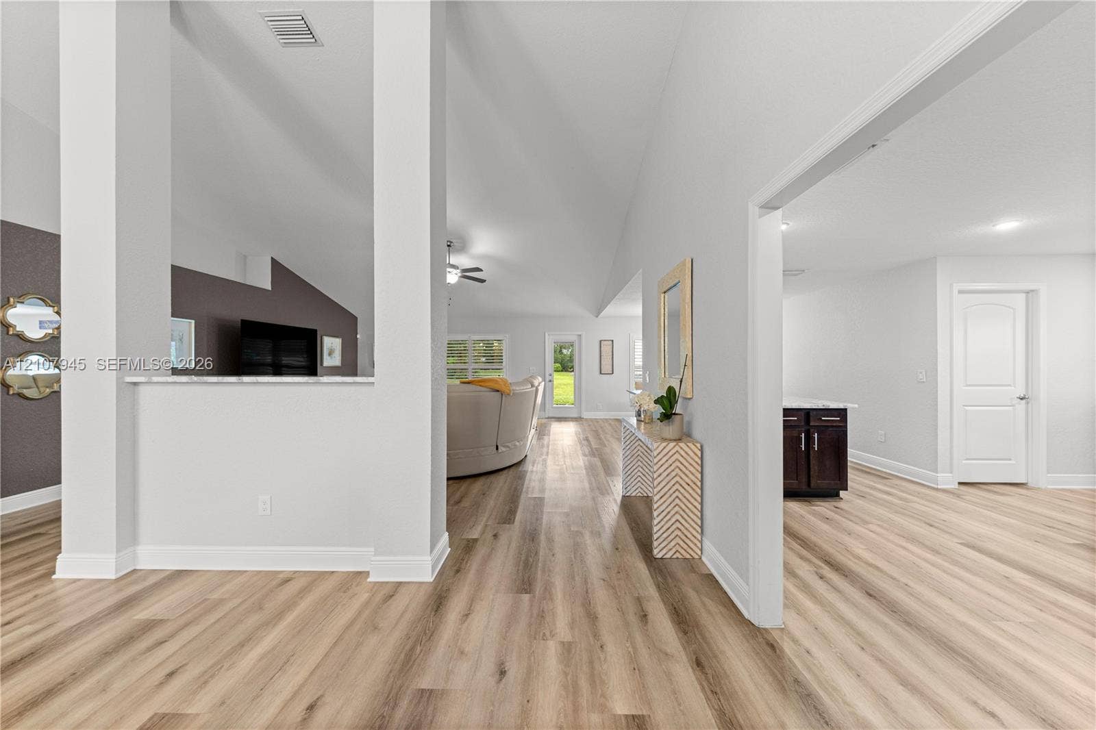 Vaulted ceilings, wood-finish flooring, and a partial architectural wall with a stone-top ledge