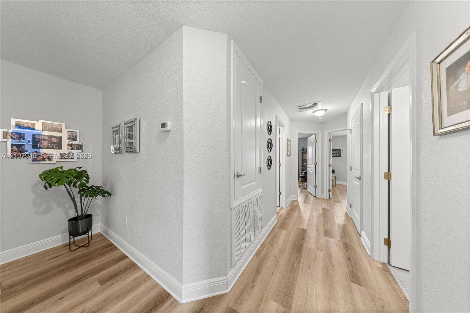 Hallway featuring wood-finish flooring, white paneled doors, and neutral wall tones