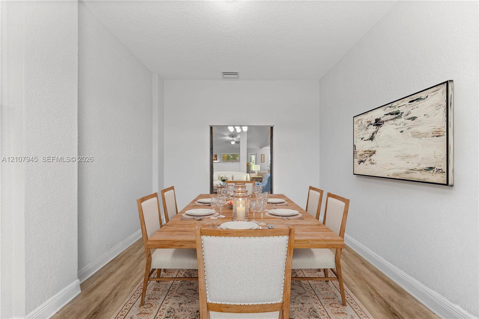 Neutral walls, wood-finish flooring, and a rectangular portal featuring interior architectural trim