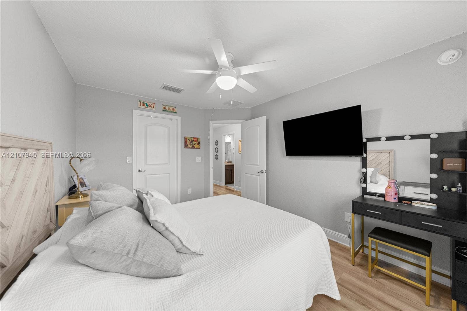 Room featuring wood-finish flooring, a white ceiling fan with integrated lighting, and two-panel interior doors