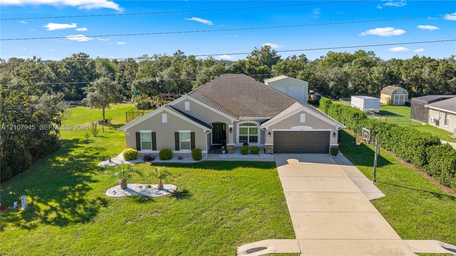 Single-story residence featuring a neutral-toned stucco exterior, hip roofline, multi-car garage, concrete driveway, and expansive lawn