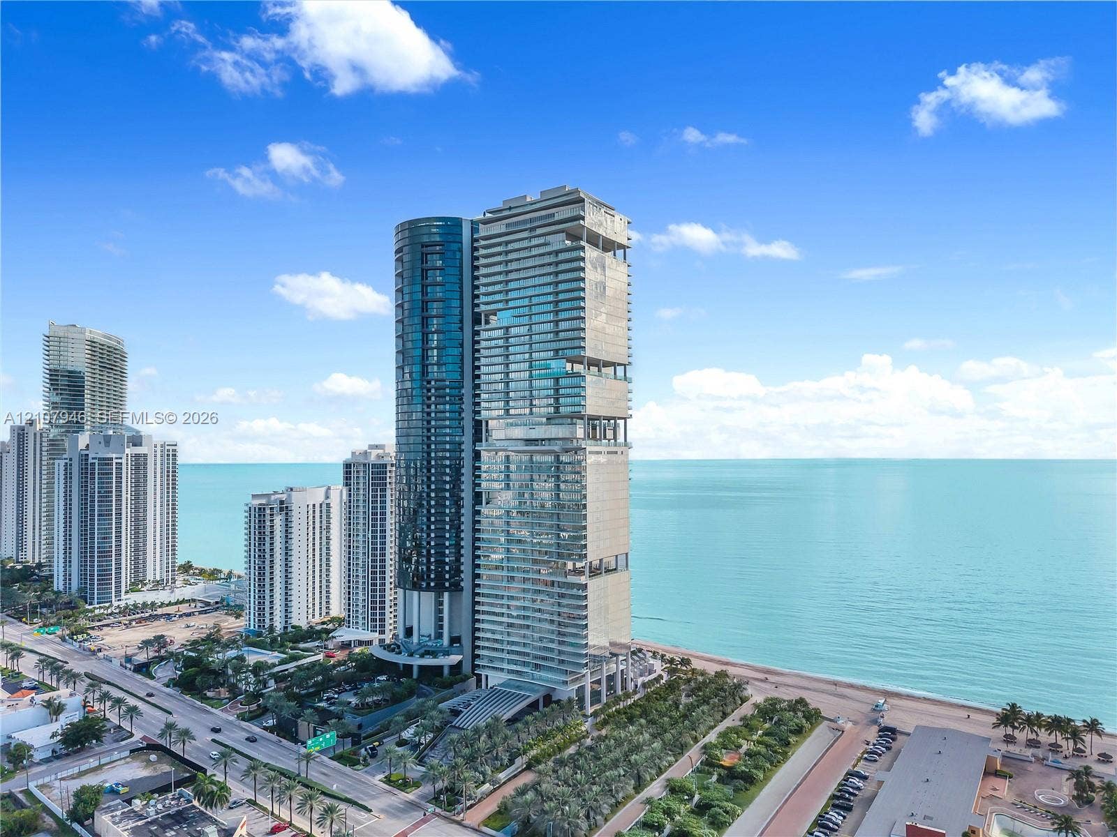 High-rise residential tower featuring a glass facade, recessed balconies, and direct proximity to the oceanfront