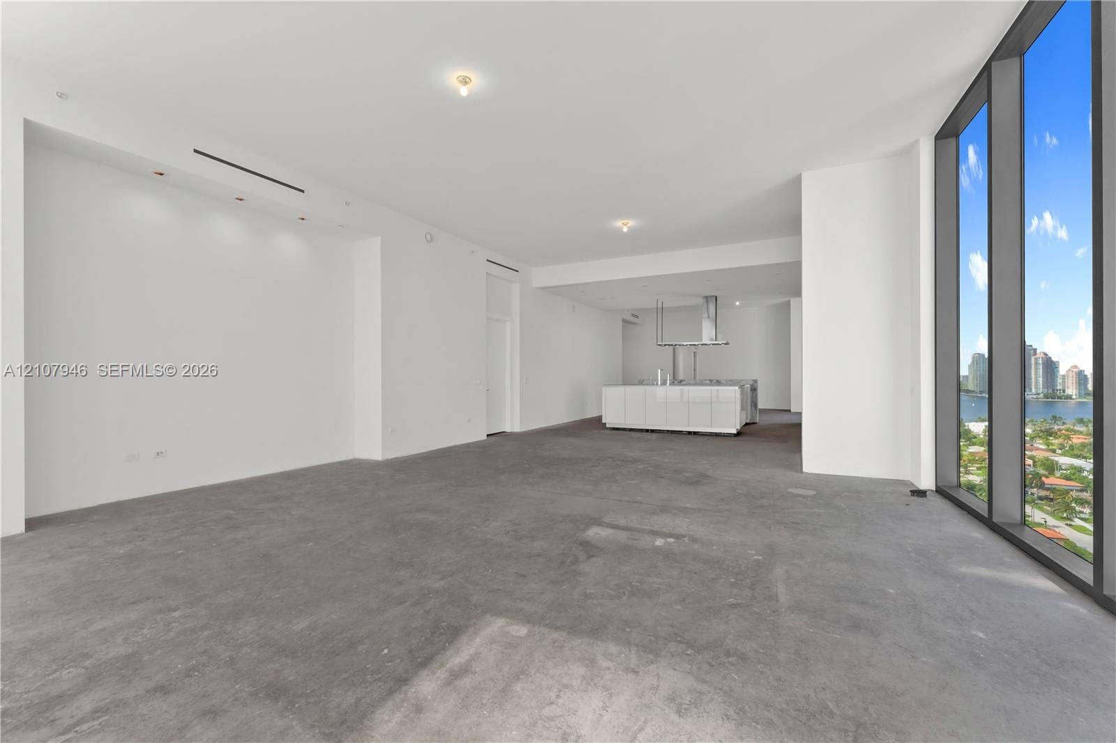 Open-concept interior featuring floor-to-ceiling windows, concrete flooring, recessed lighting, and a white kitchen island with a stainless steel range hood