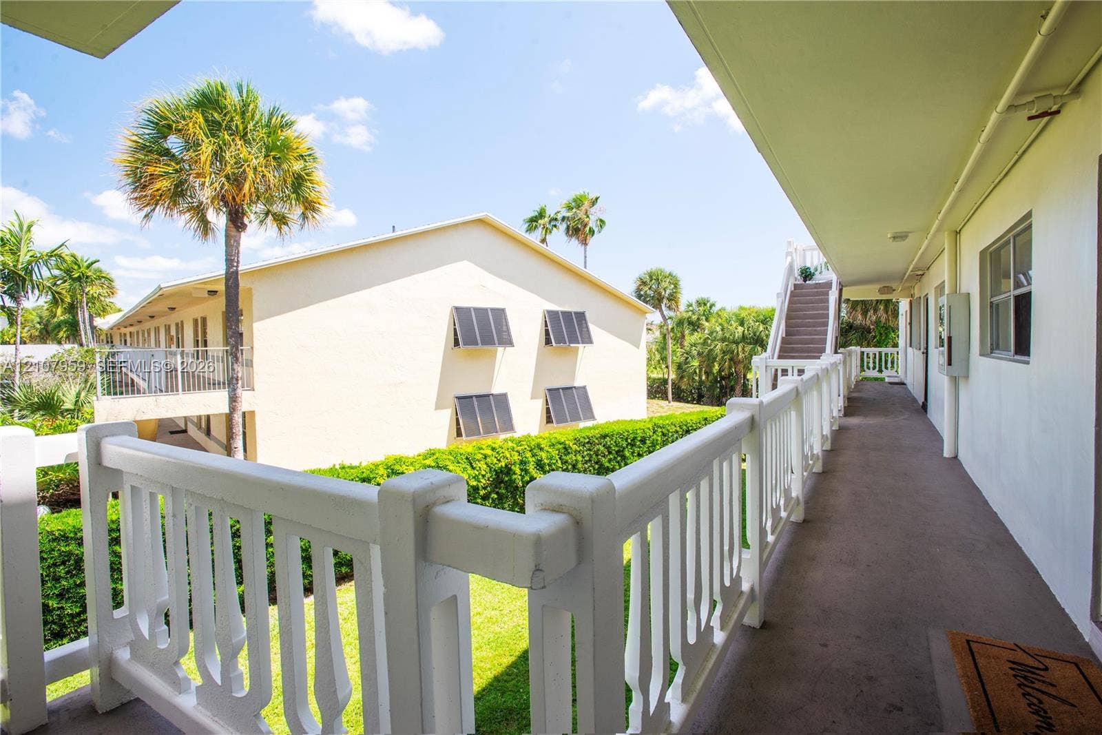 4200 Crystal Lake Drive, #204, Deerfield Beach, Deerfield Beach, FL 33064 Exterior walkway featuring a white decorative balustrade, paved flooring, and stairwell access