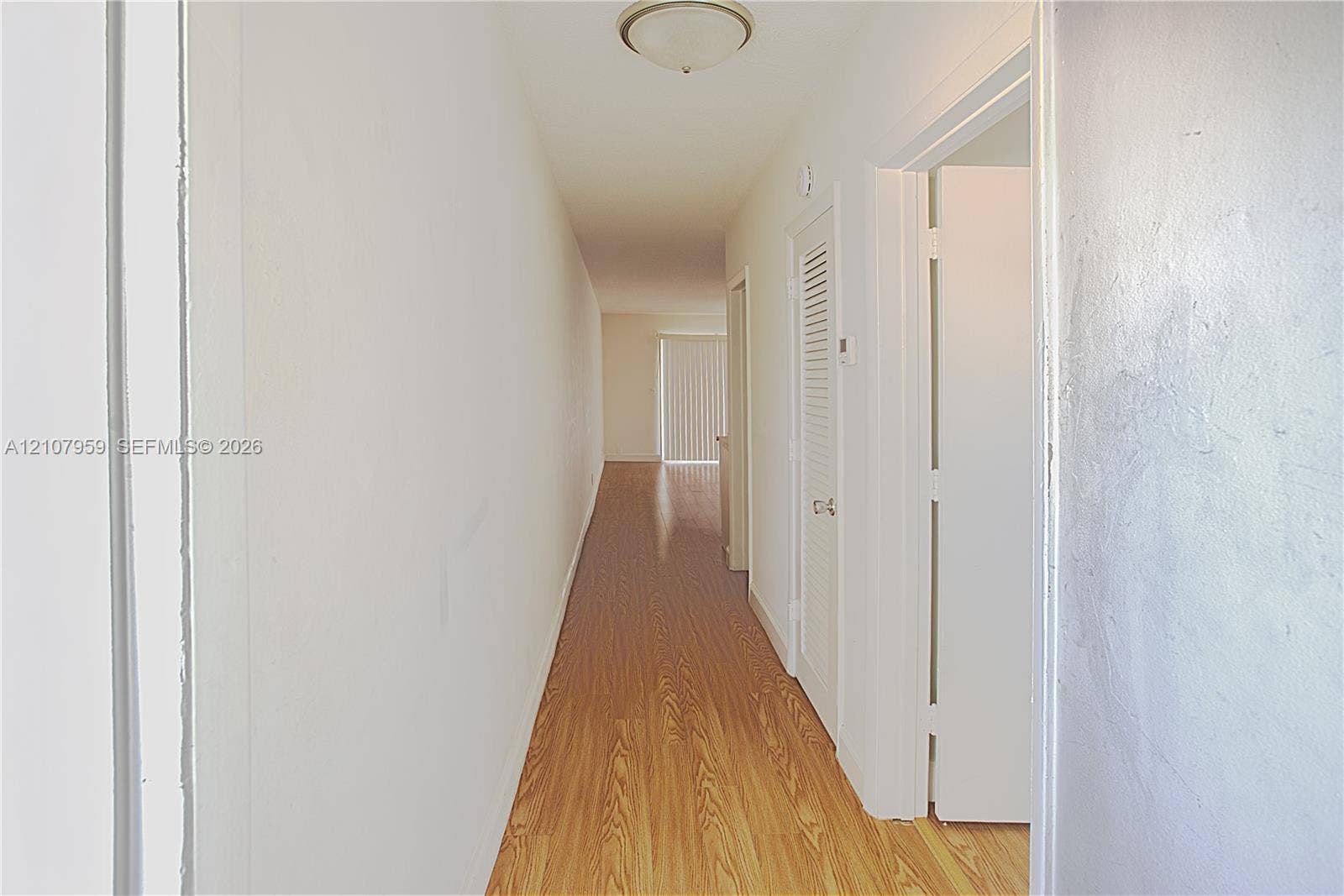 4200 Crystal Lake Drive, #204, Deerfield Beach, Deerfield Beach, FL 33064 Hallway featuring wood-finish flooring, flush-mount ceiling lighting, and louvered closet doors