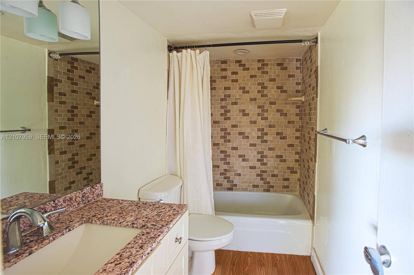 4200 Crystal Lake Drive, #204, Deerfield Beach, Deerfield Beach, FL 33064 Bathroom featuring a vanity with a stone-finish countertop, undermount sink, multi-tonal tile shower surround, and wood-finish flooring
