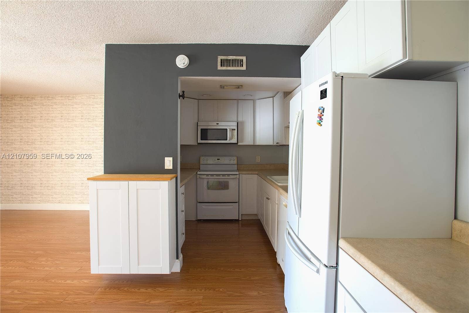 4200 Crystal Lake Drive, #204, Deerfield Beach, Deerfield Beach, FL 33064 Kitchen area featuring white shaker-style cabinetry, wood-finish flooring, a built-in microwave, and a range