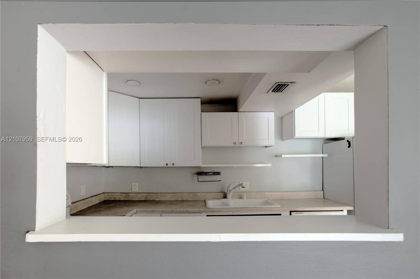 4200 Crystal Lake Drive, #204, Deerfield Beach, Deerfield Beach, FL 33064 Pass-through opening featuring white cabinetry, solid-surface countertops, recessed lighting, and a white sink